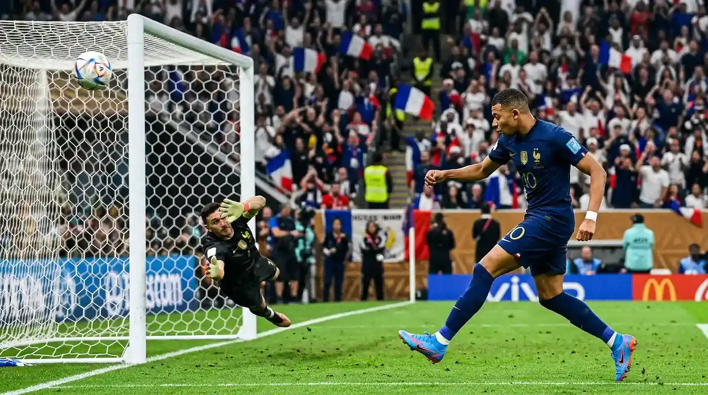 Mbappé en acción durante un partido del Mundial 2026, definiendo de potente disparo ante el arquero rival que intenta atajar sin éxito